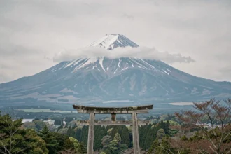 Volcan japonais emblématique avec torii traditionnel au premier plan et sommet enneigé sous les nuages